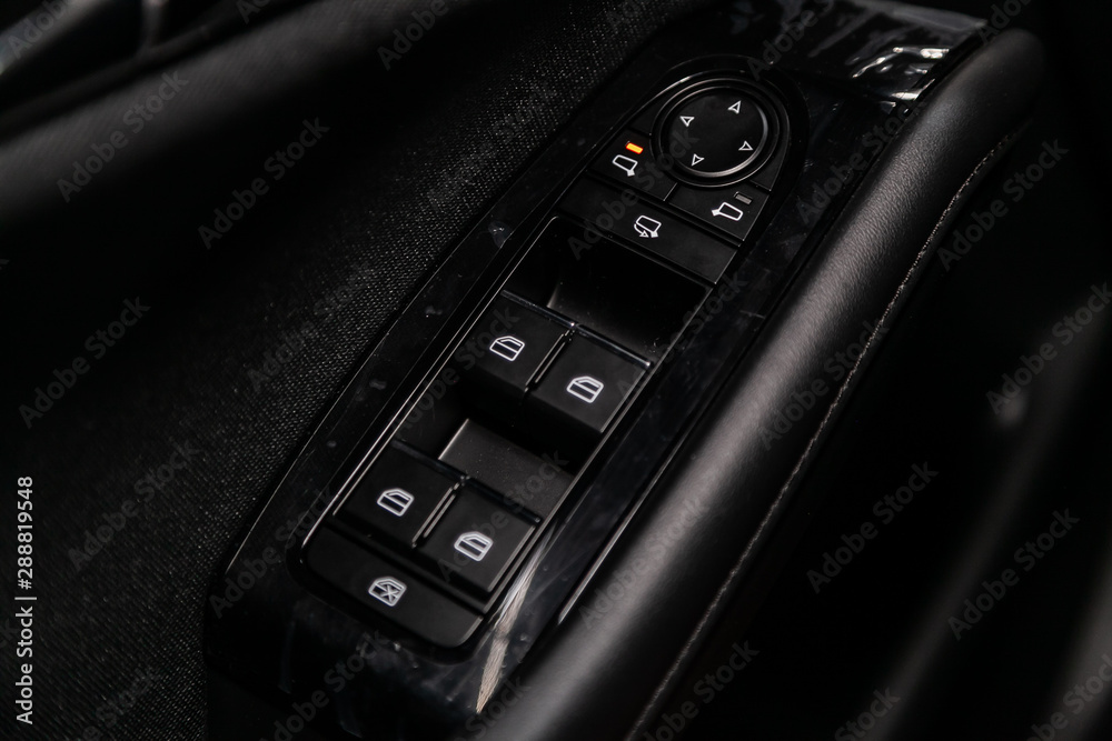 Close up of a door control panel in a new modern car. Arm rest with window control panel, door lock button, and mirror control..