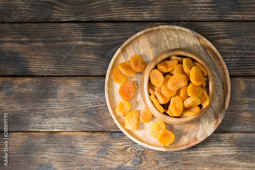 Dried apricots in a wooden bowl on a wooden table