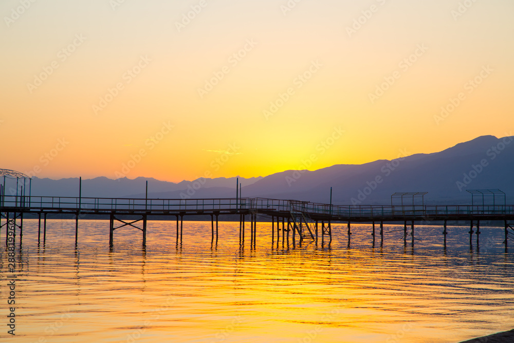 Beautiful sunset on a lake in the mountains. Kyrgyzstan, Issyk-Kul Lake. Bright sky, background in warm colors. Beautiful sunset on a lake in the mountains. Kyrgyzstan, Issyk-Kul Lake. Bright sky, background in warm colors.