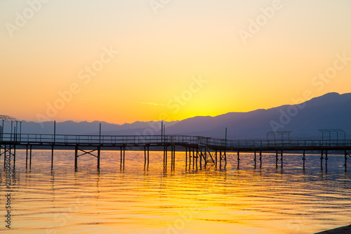 Beautiful sunset on a lake in the mountains. Kyrgyzstan  Issyk-Kul Lake. Bright sky  background in warm colors.