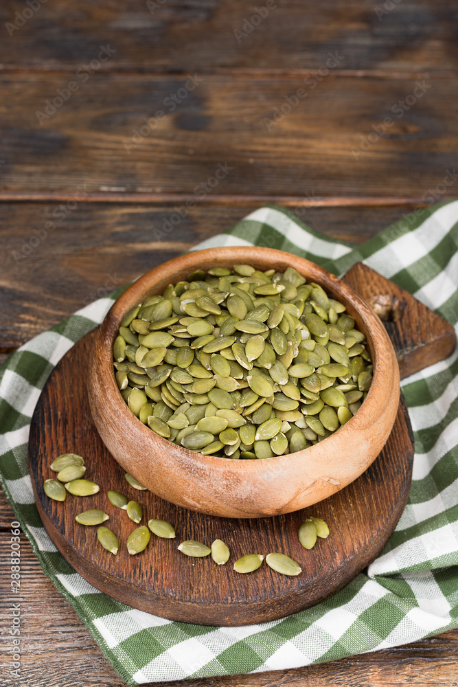 Pumpkin seeds in a wooden bowl on a wooden table