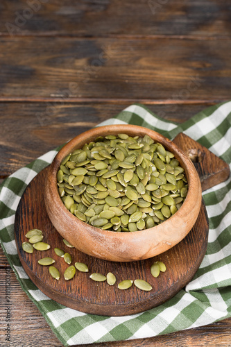 Pumpkin seeds in a wooden bowl on a wooden table