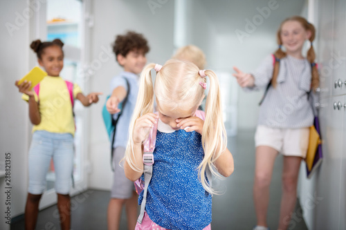 Little girl crying while feeling offended by classmates