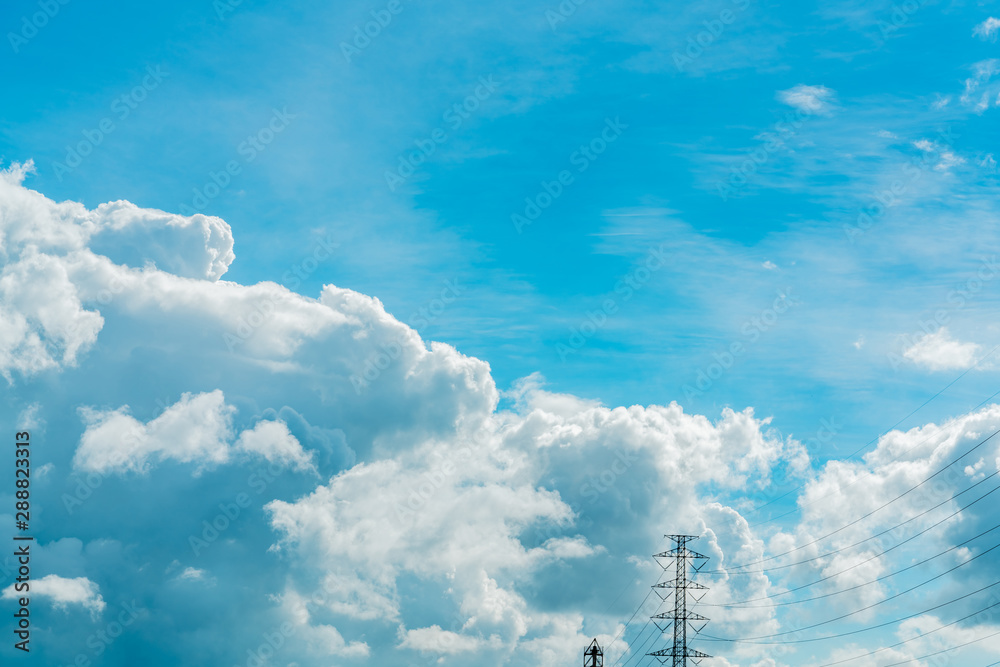 Beautiful blue sky and white cumulus clouds above transmission lines and high voltage electric tower. Cloudscape background. Blue sky and fluffy white clouds on sunny day. Nature background. Beautiful blue sky and white cumulus clouds above transmission lines and high voltage electric tower. Cloudscape background. Blue sky and fluffy white clouds on sunny day. Nature background.