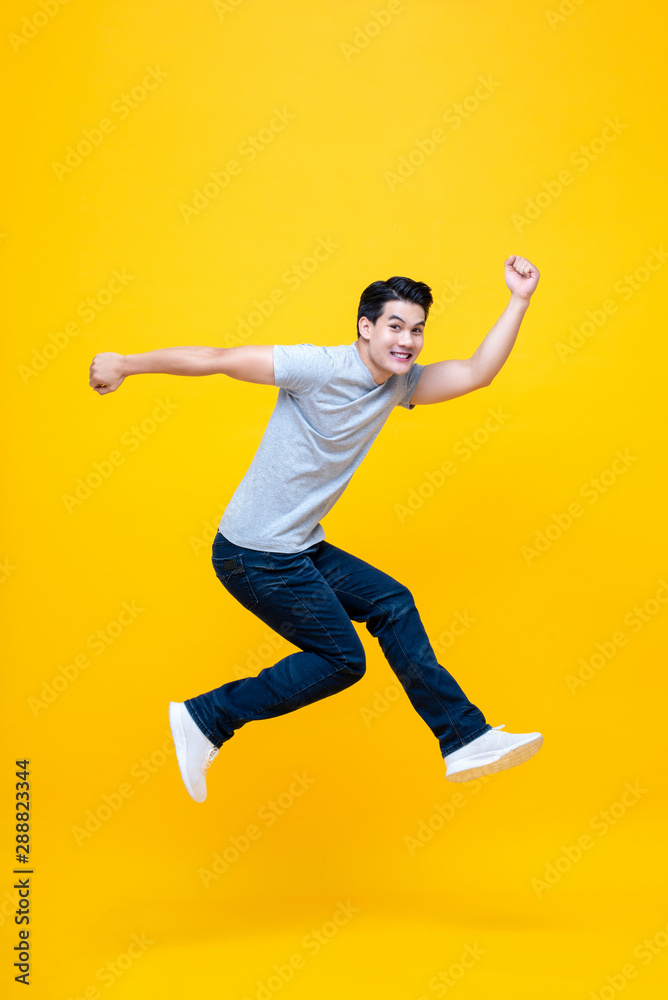 Fun energetic young handsome Asian man jumping in mid-air