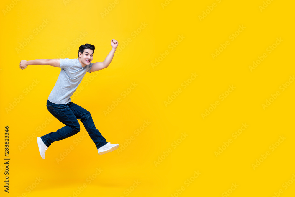 Fun energetic young handsome Asian man jumping in mid-air