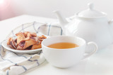 Cup of tea with cookies over lilac wooden background