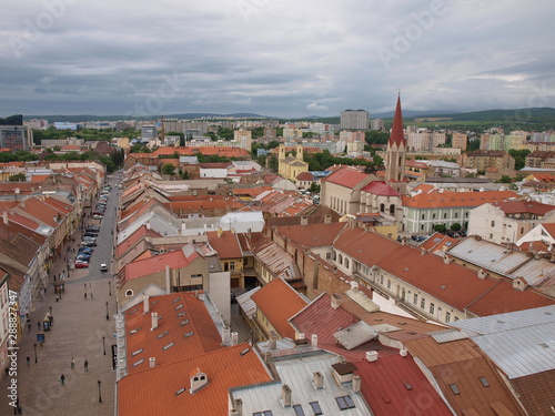 view of the old part of the city from above, on the roofs of houses made of brown tiles, the spire of the Church and the street.