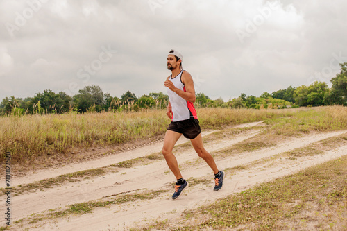 Man running outdoors with a beard in a sports uniform in nature, day, open air