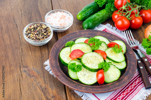 Diet salad of fresh cucumbers and tomatoes, cut into slices on wooden table