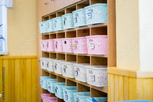 Classroom interior in junior high school. Window and flowers on windowsill. On the wall is a rack with boxes containing tools for creativity and learning. Empty class after class.