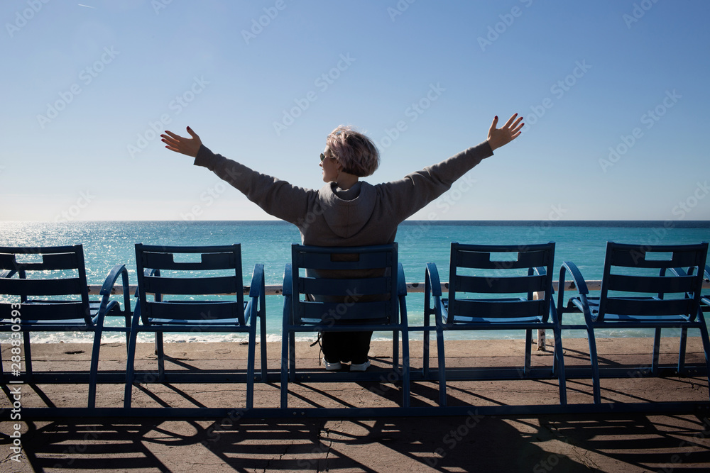 Young woman sitting on a bench near the shores of the Mediterranean Sea Young woman sitting on a bench near the shores of the Mediterranean Sea