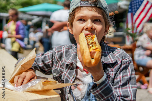 Quadro su tela Boy eating barbecue grilled hot dog on family picnic celebrating independence da