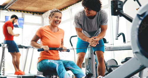 Fotografie Young beautiful woman doing exercises with personal trainer