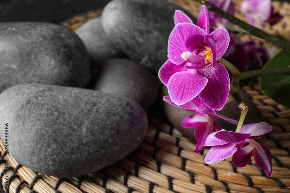Composition with orchid flowers and spa stones on wicker mat Composition with orchid flowers and spa stones on wicker mat