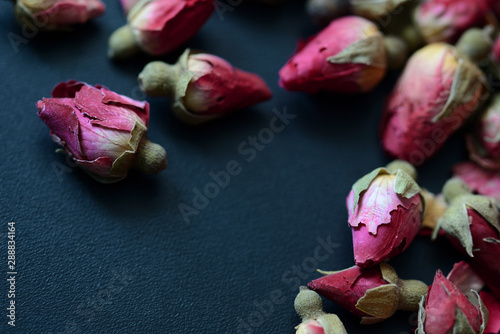 Dried rose buds scattered on a dark surface. Rose tea close up