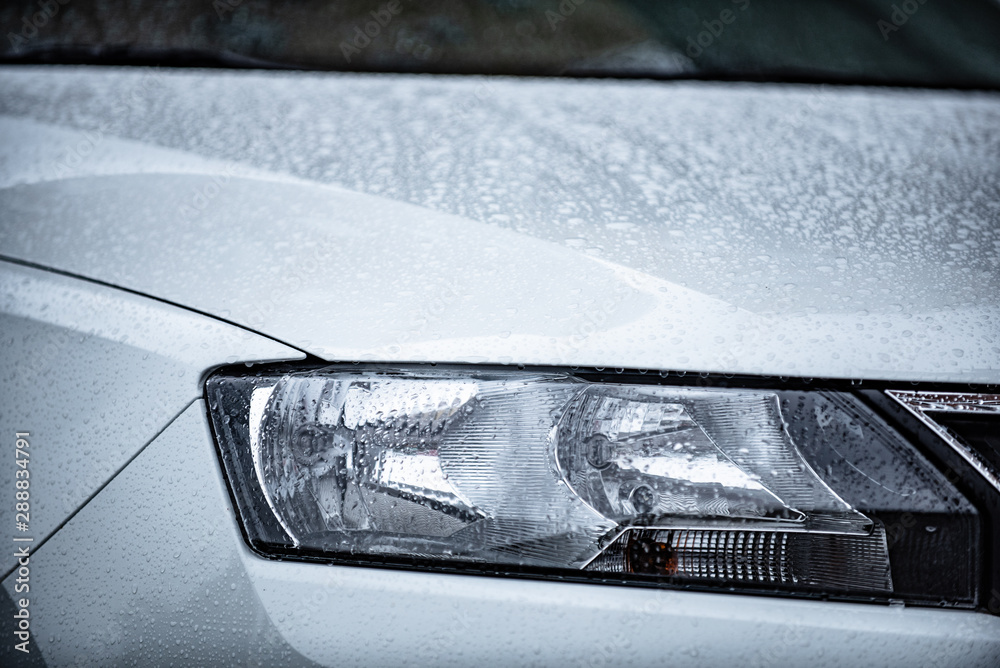 view of the front of a white car with water drops after rain. Concept on the topic of polishing a car.