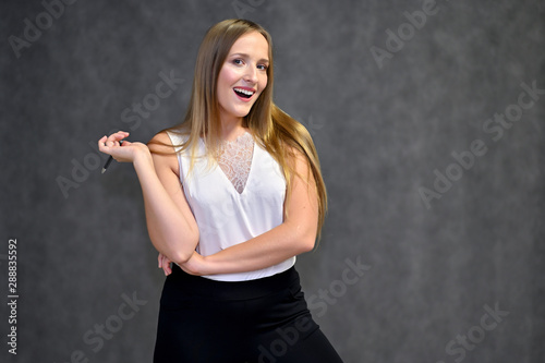 Business photo portrait of a young woman in a business suit on a gray background. Well-groomed hair, slim figure. It is in different poses.