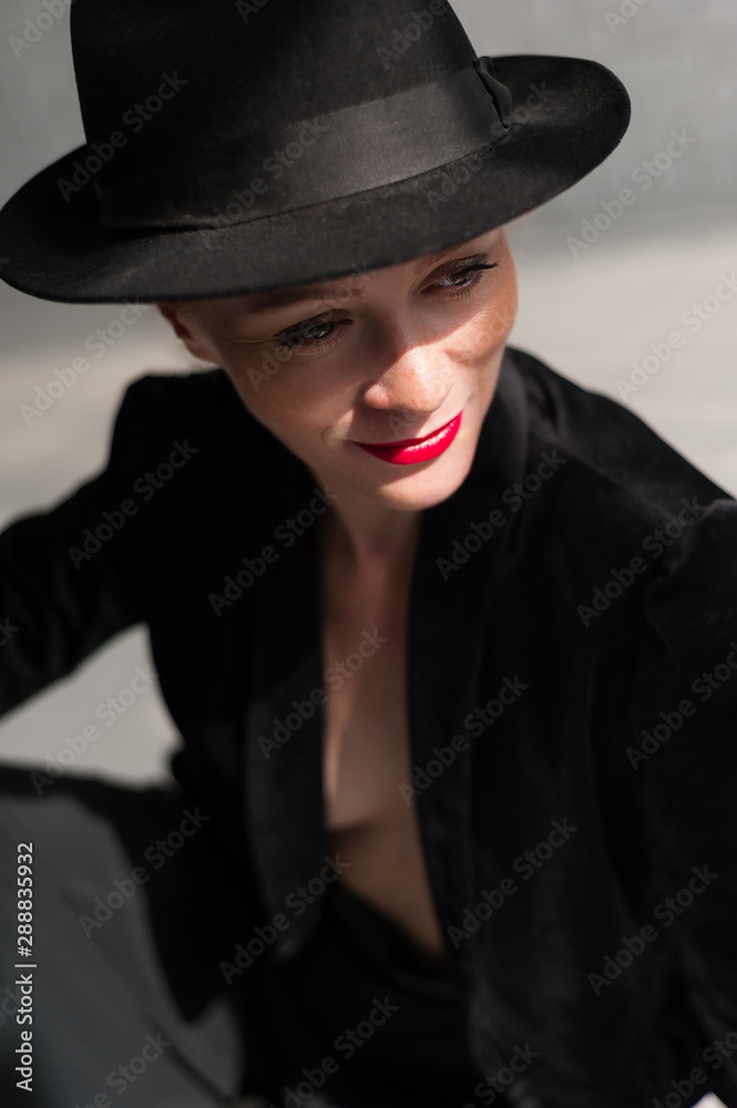 Girl posing in a black hat on the background of sunlight Girl posing in a black hat on the background of sunlight