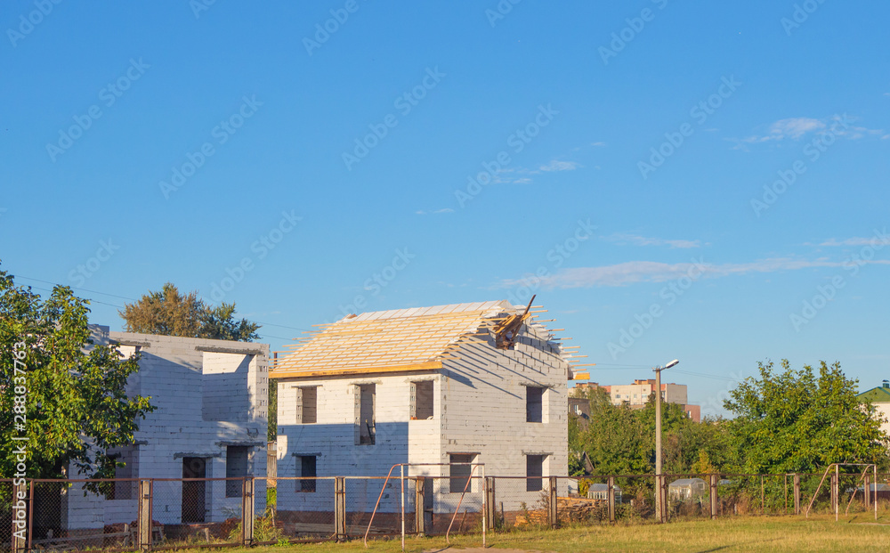 New house under construction with missing windows and unfinished roof. House frame New house under construction with missing windows and unfinished roof. House frame