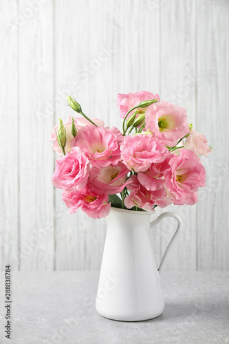 Eustoma flowers in vase on table near white wall