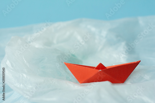 Red paper boat on plastic bag.