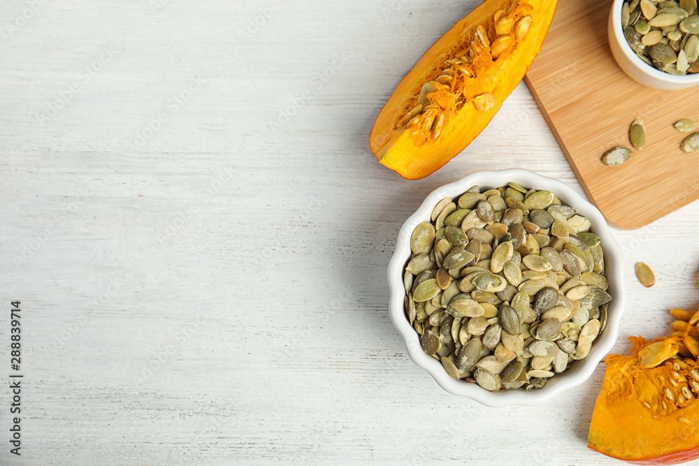 Flat lay composition with raw pumpkin seeds on white wooden table, space for text Flat lay composition with raw pumpkin seeds on white wooden table, space for text