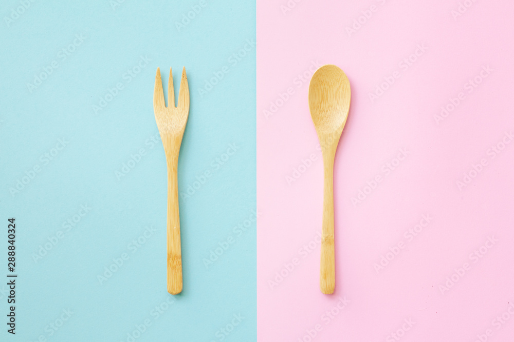 Flat lay wooden spoon with plastic spoon on pink and blue background.sustainable lifestyle and zero waste concept Flat lay wooden spoon with plastic spoon on pink and blue background.sustainable lifestyle and zero waste concept