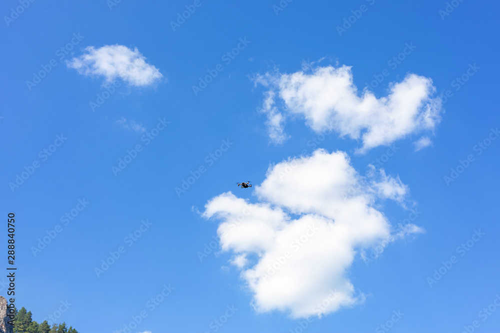 Flight of the drone against the blue sky on a sunny day. quadcopter flying through the sky. New aerial photo and video technology Flight of the drone against the blue sky on a sunny day. quadcopter flying through the sky. New aerial photo and video technology