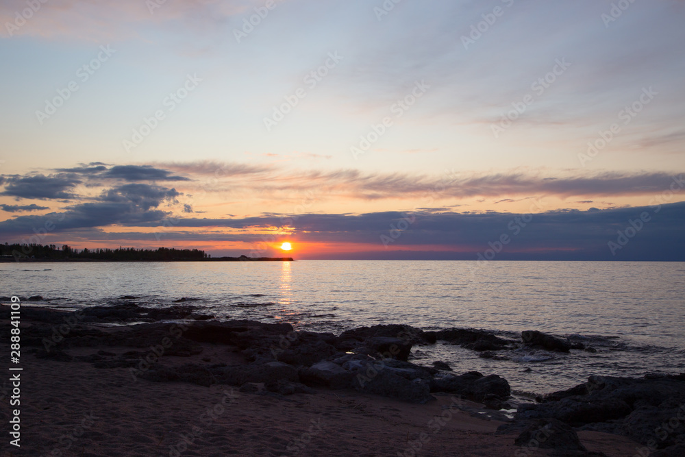 Beautiful sunset on a lake in the mountains. Kyrgyzstan, Issyk-Kul Lake. Bright sky, background in warm colors.