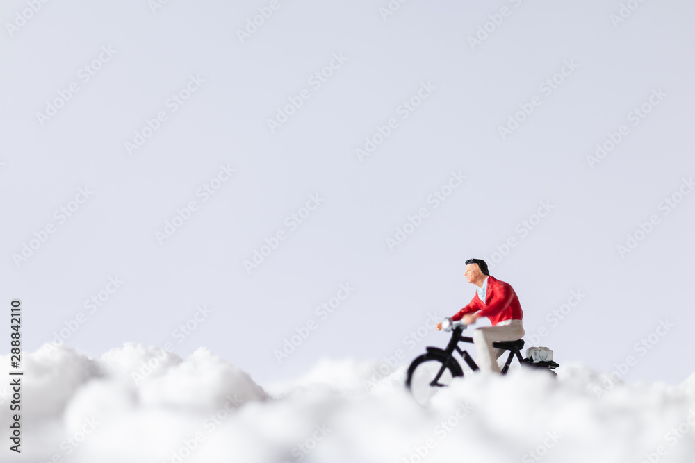  Miniature people : Travelers riding a bicycle on snow , winter background concept