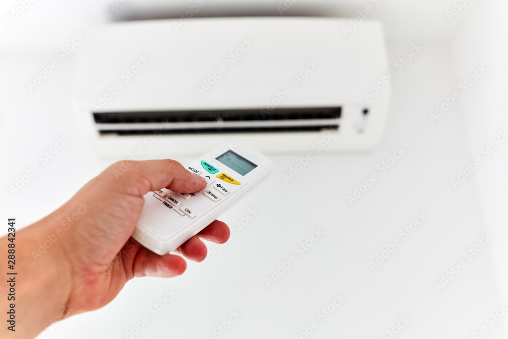 Modern air conditioner unit with a hand holding a remote. Modern air conditioner unit with a hand holding a remote.