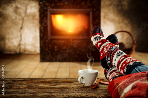 Woman legs with christmas socks and home interior with fireplace 