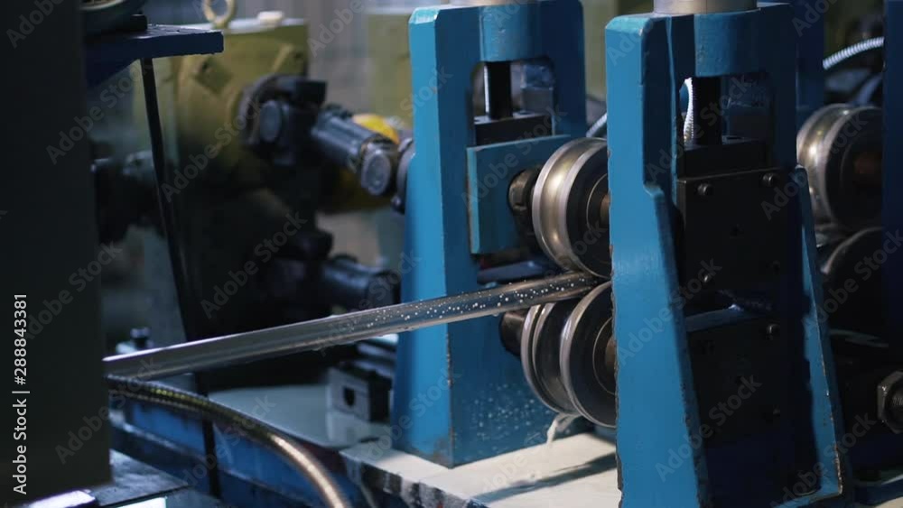 Sophisticated machine with pressure rollers forms a pipe from a sheet of metal