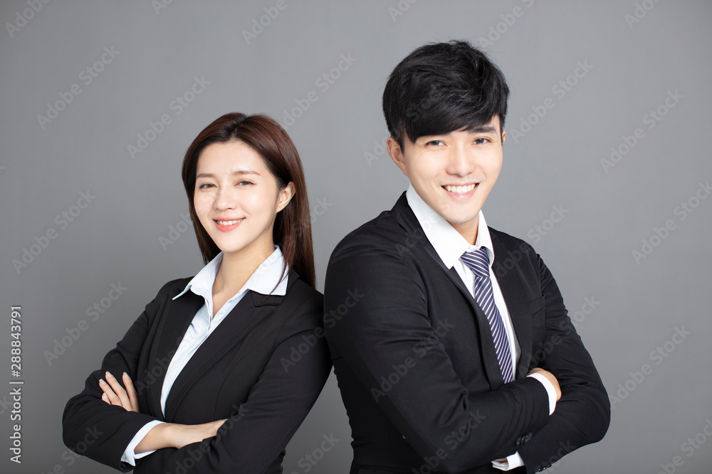 business man and woman standing back to back with crossed hands against gray background business man and woman standing back to back with crossed hands against gray background