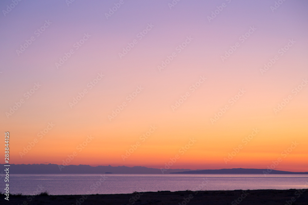 Dawn on a lake in the mountains. rays of the rising sun, orange color. Kyrgyzstan, Issyk-Kul Lake. Bright sky, background in warm colors. Dawn on a lake in the mountains. rays of the rising sun, orange color. Kyrgyzstan, Issyk-Kul Lake. Bright sky, background in warm colors.