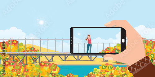 Make a photo of woman landscape by smartphone in autumn.
