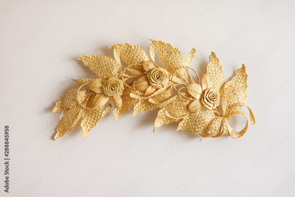 Decoration of straw on a white background. Branch with leaves and flowers is made of straw. Decor. Closeup Decoration of straw on a white background. Branch with leaves and flowers is made of straw. Decor. Closeup