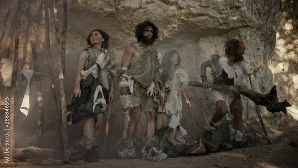 Tribe of Four Hunter-Gatherers Wearing Animal Skin Holding Stone Tipped Tools, Pose at the Entrance of their Cave. Portrait of Two Grown Male and Two Female Neanderthals and their Way of Living. Tribe of Four Hunter-Gatherers Wearing Animal Skin Holding Stone Tipped Tools, Pose at the Entrance of their Cave. Portrait of Two Grown Male and Two Female Neanderthals and their Way of Living.
