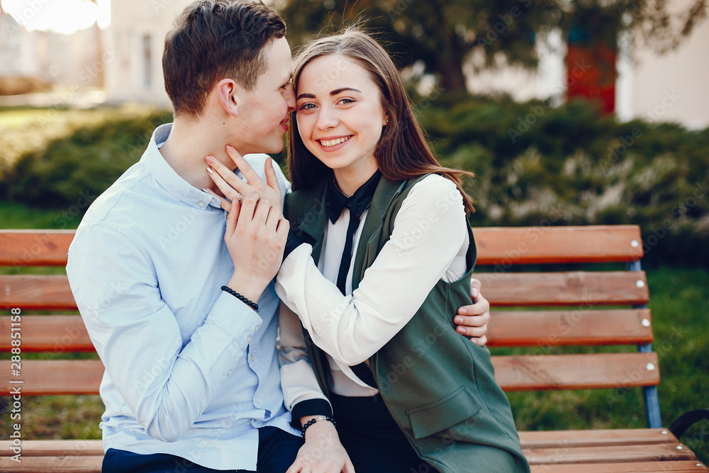handsome young guy in a blue shirt sitting on a bench in a sunny summer city along with her cute girl in a white shirt handsome young guy in a blue shirt sitting on a bench in a sunny summer city along with her cute girl in a white shirt