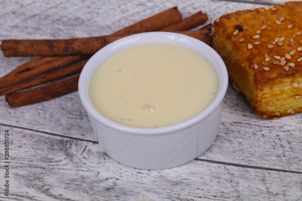 Condenced milk in the bowl with sinnamon and pastry Condenced milk in the bowl with sinnamon and pastry