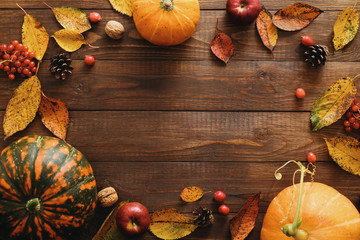 Autumn frame made of pumpkins, dried fall leaves, apples, red berries, walnuts, pine cones on wooden table. Thanksgiving, Halloween, Autumn Harvest concept. Flat lay composition, top view, copy space