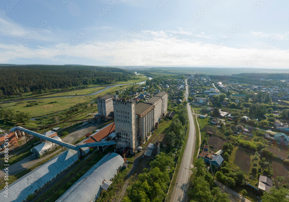 Elevator of flour mill and Iset river in Aramil village. Aerial, summer, sunny