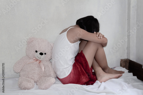 Fototapeta traumatized teenage girl sitting on the bed,Stop violence and abused children concept
