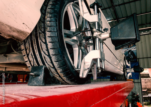 Tire clamped with lazer aligner undergoing auto wheel alignment in modern garage