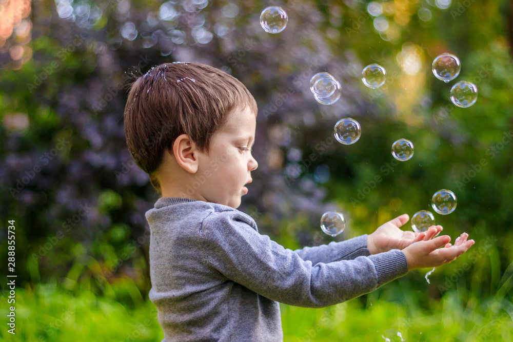 A boy on the street catches soap bubbles. Happy childhood. Children's games. A boy on the street catches soap bubbles. Happy childhood. Children's games.