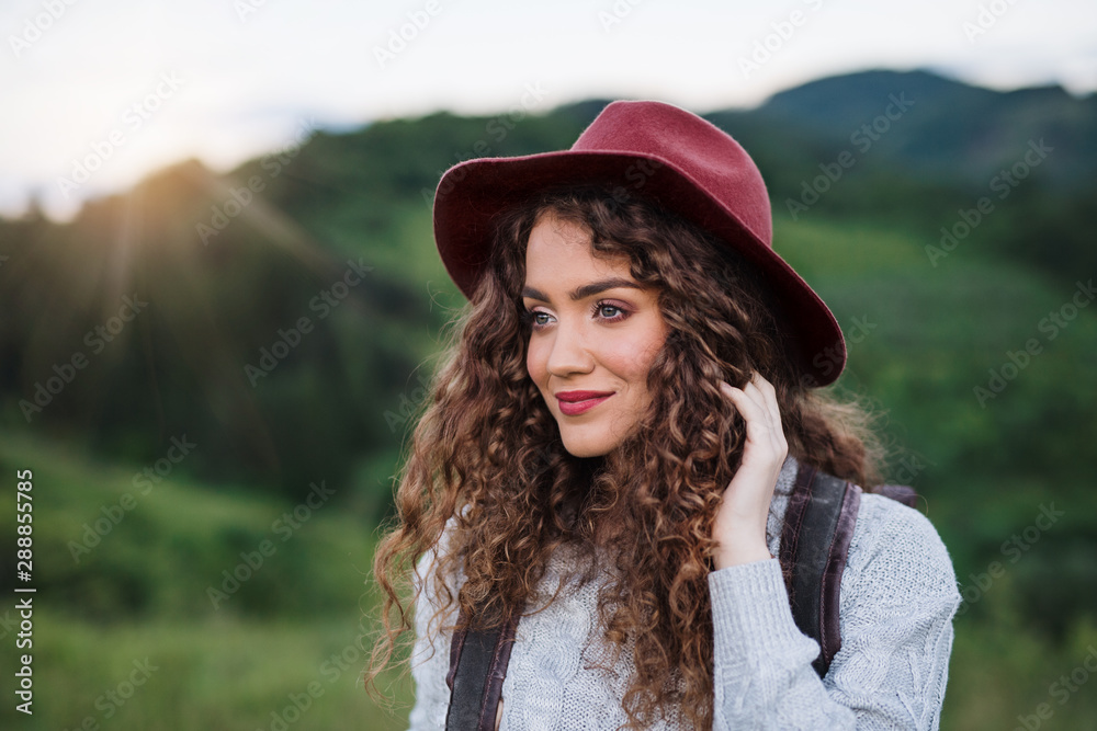 Young tourist woman traveller with backpack walking in nature at sunset.