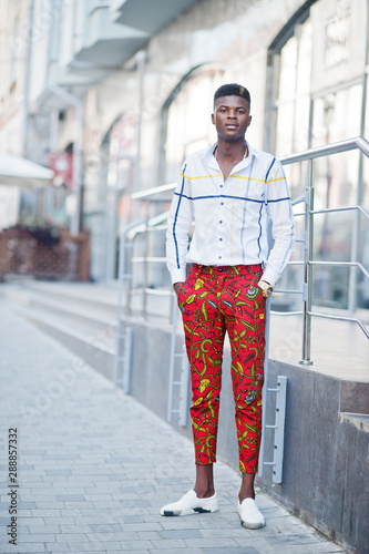 Portrait of handsome stylish african american model man in red throusers and white shirt. photo