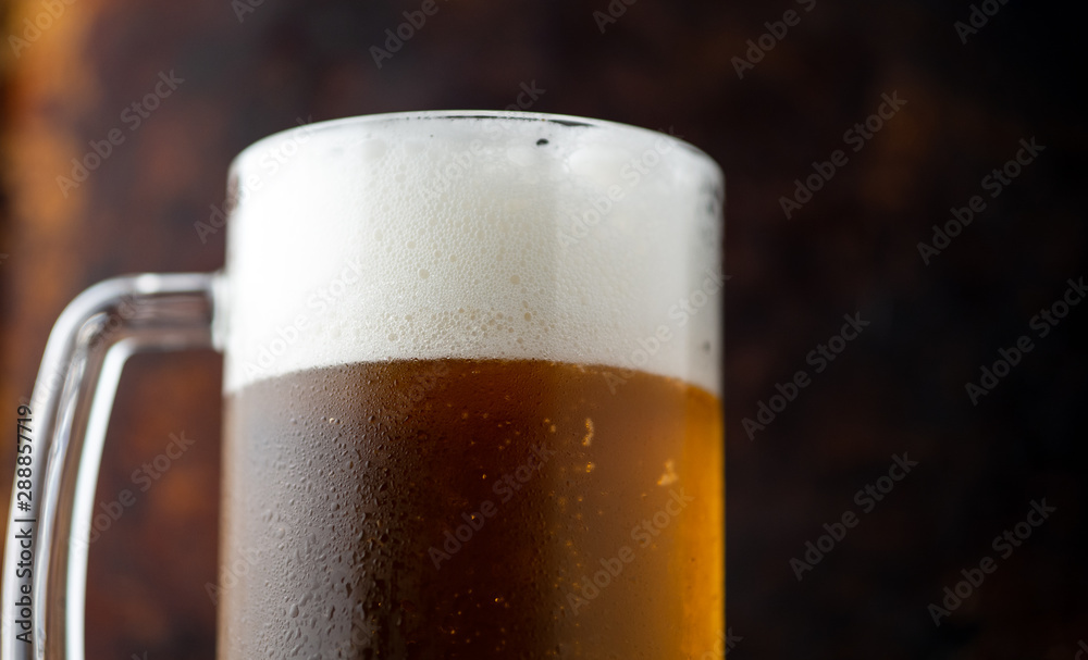 Mug of light beer with drops of water on a dark rusty background Mug of light beer with drops of water on a dark rusty background