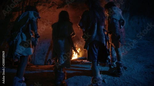 Wallpaper Mural Tribe of Prehistoric Hunter-Gatherers Wearing Animal Skins Live in a Cave at Night. Neanderthal or Homo Sapiens Family Trying to Get Warm at the Bonfire, Holding Hands over Fire. Following Back View Torontodigital.ca